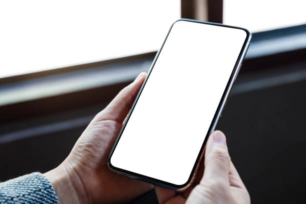 Mockup image of a woman holding mobile phone with blank white desktop screen