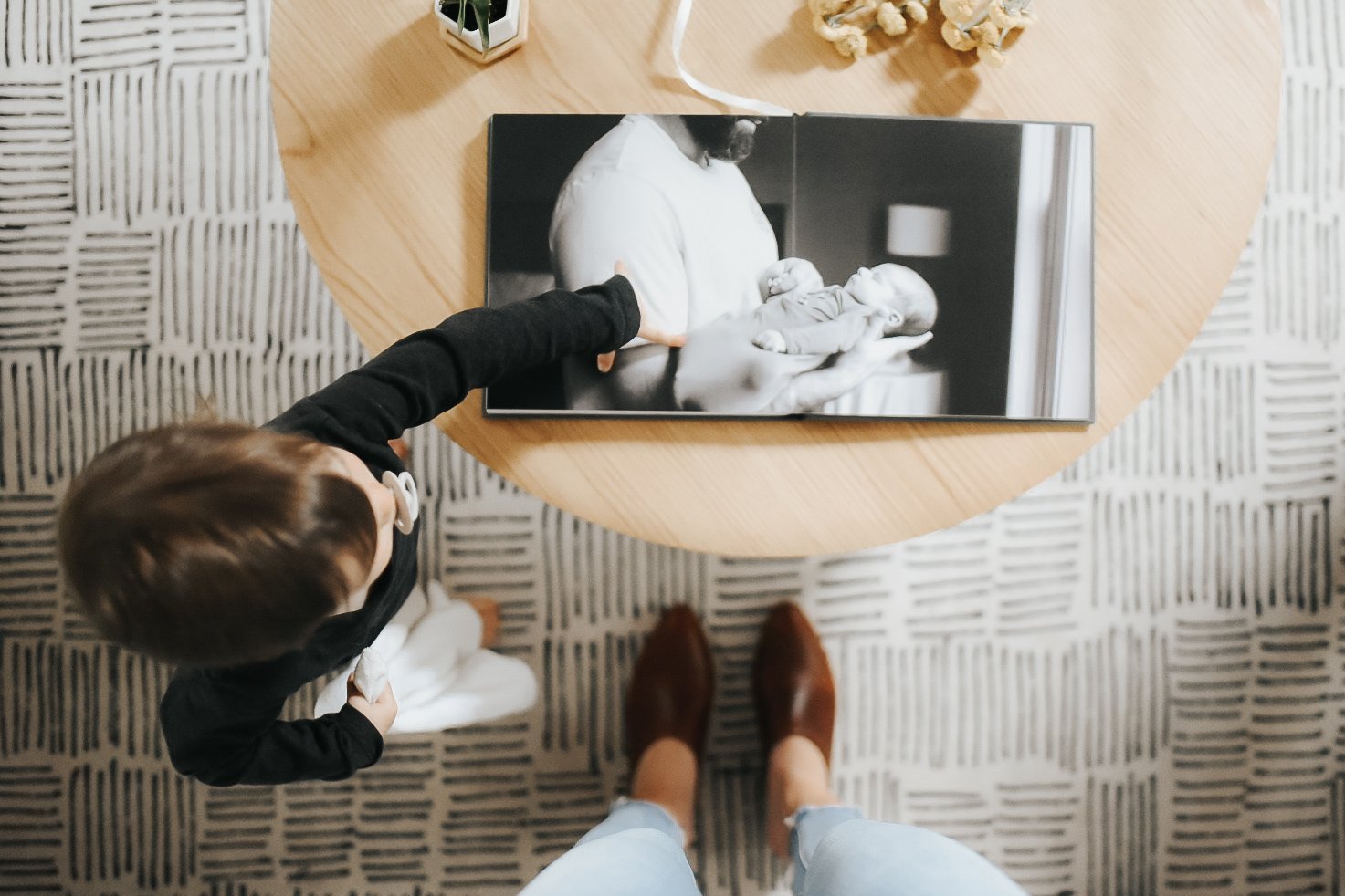 little boy pointing at a photo album of him and his father